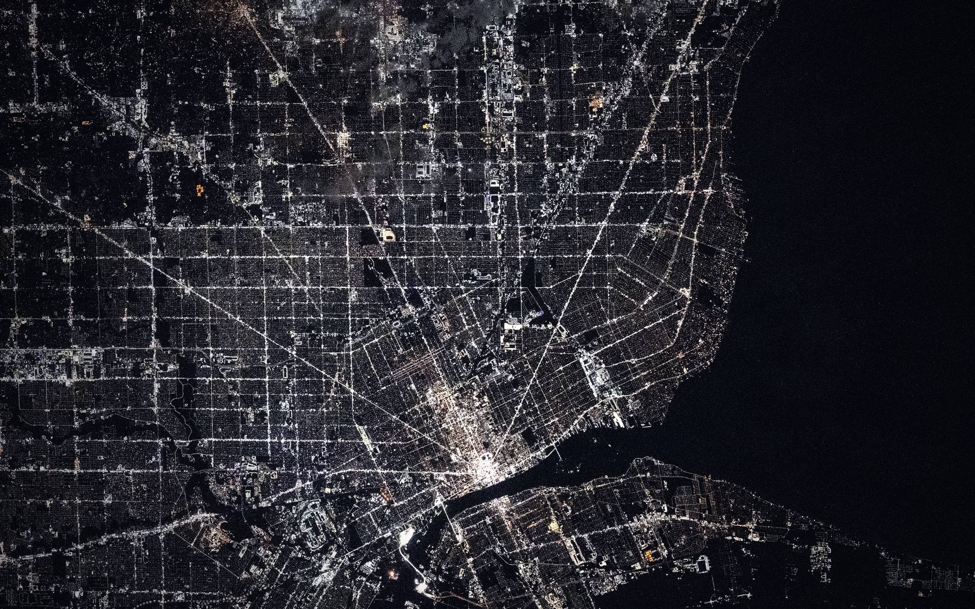 Detroit at night, photographed from the International Space Station. Woodward and Gratiot Avenues glow amber and meet downtown in a V.